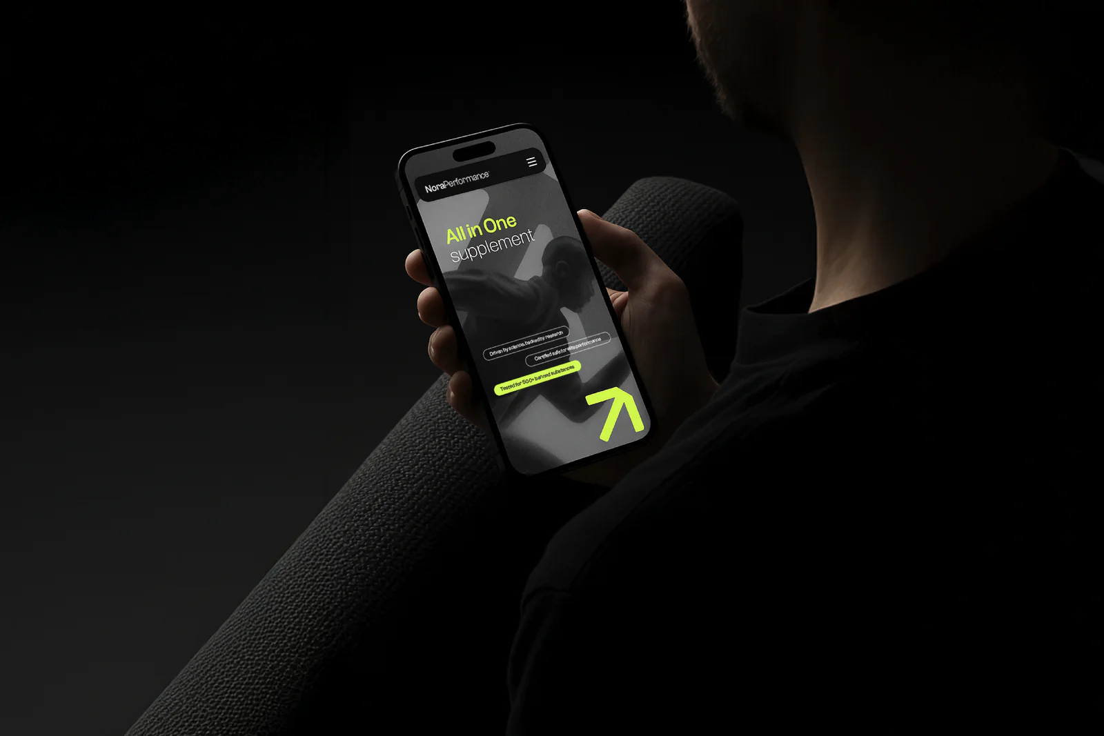 Site web mobile Nora Performance sur un smartphone tenu en main dans la pénombre