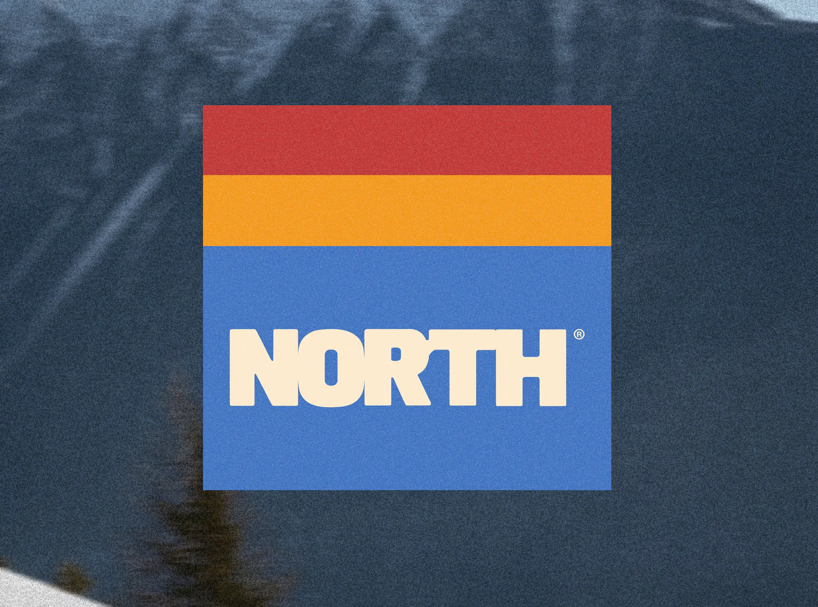 Logo NORTH® sur un bloc de bandes rouge, jaune et bleue, devant la montagne