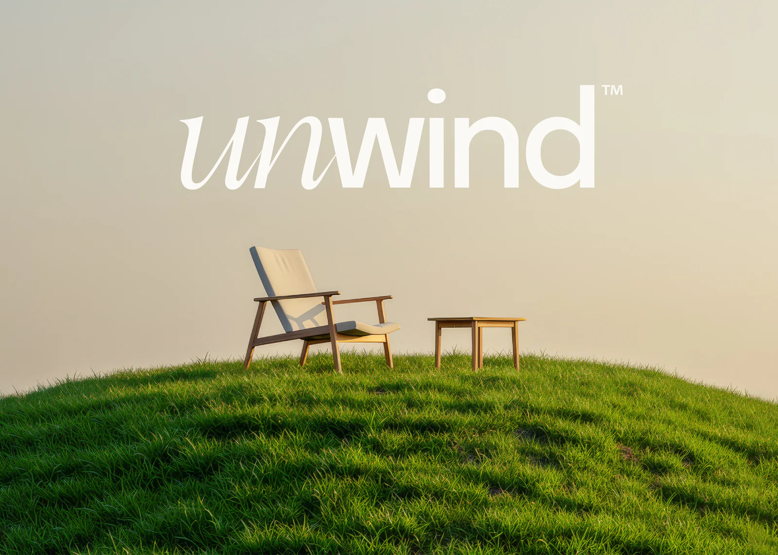 Logo Unwind au-dessus d'un fauteuil et d'une table posés sur une colline d'herbe