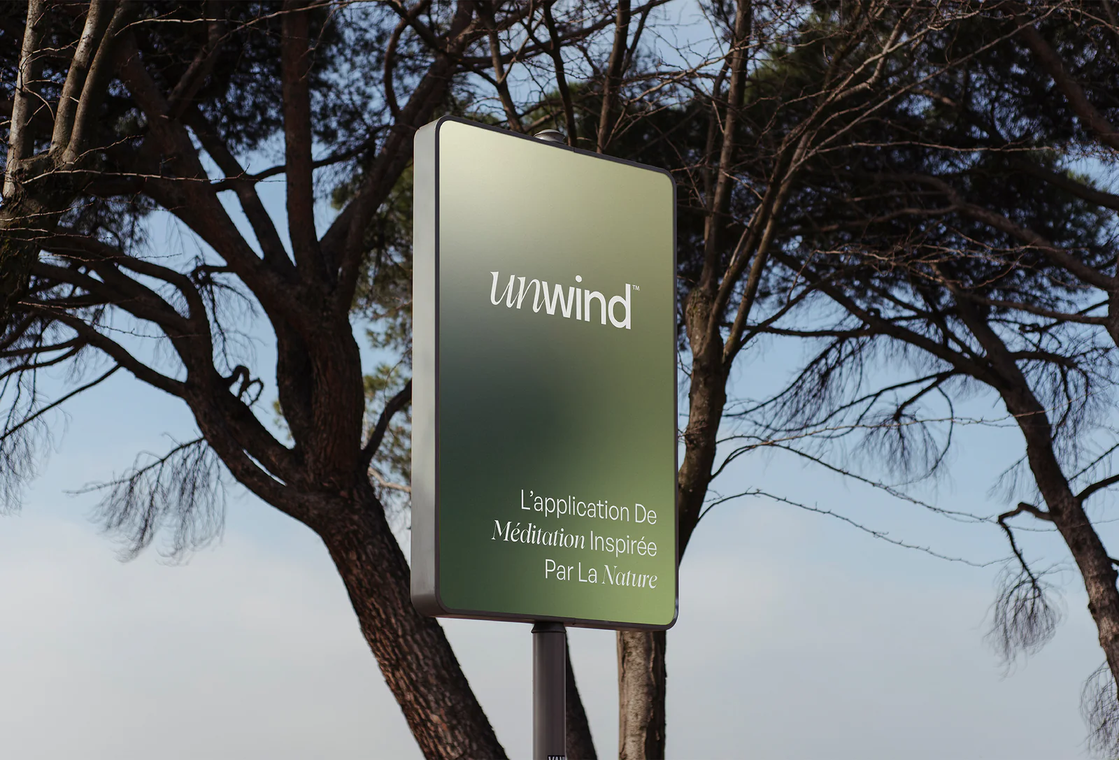 Panneau d'affichage Unwind, « L'application de méditation inspirée par la nature », entre les branches de pins
